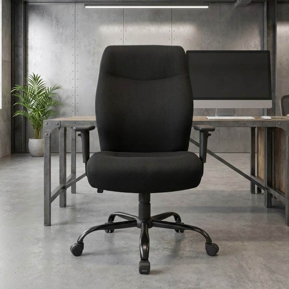 Black 24-hour fabric task chair featuring a contoured backrest, integrated lumbar pump, adjustable seat slide, and armrests, placed in an industrial-style office with concrete flooring and metal-framed desk.