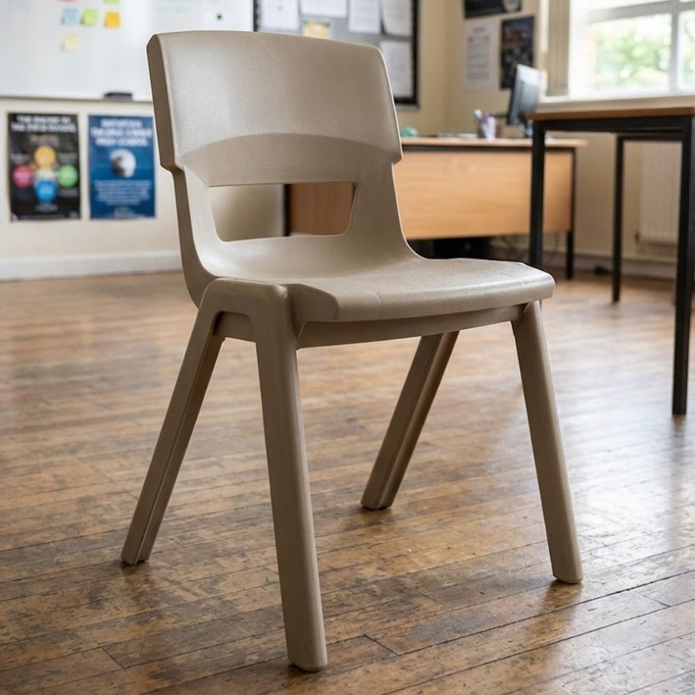 Beige plastic school chair with molded backrest, placed in a well-lit classroom with bulletin board