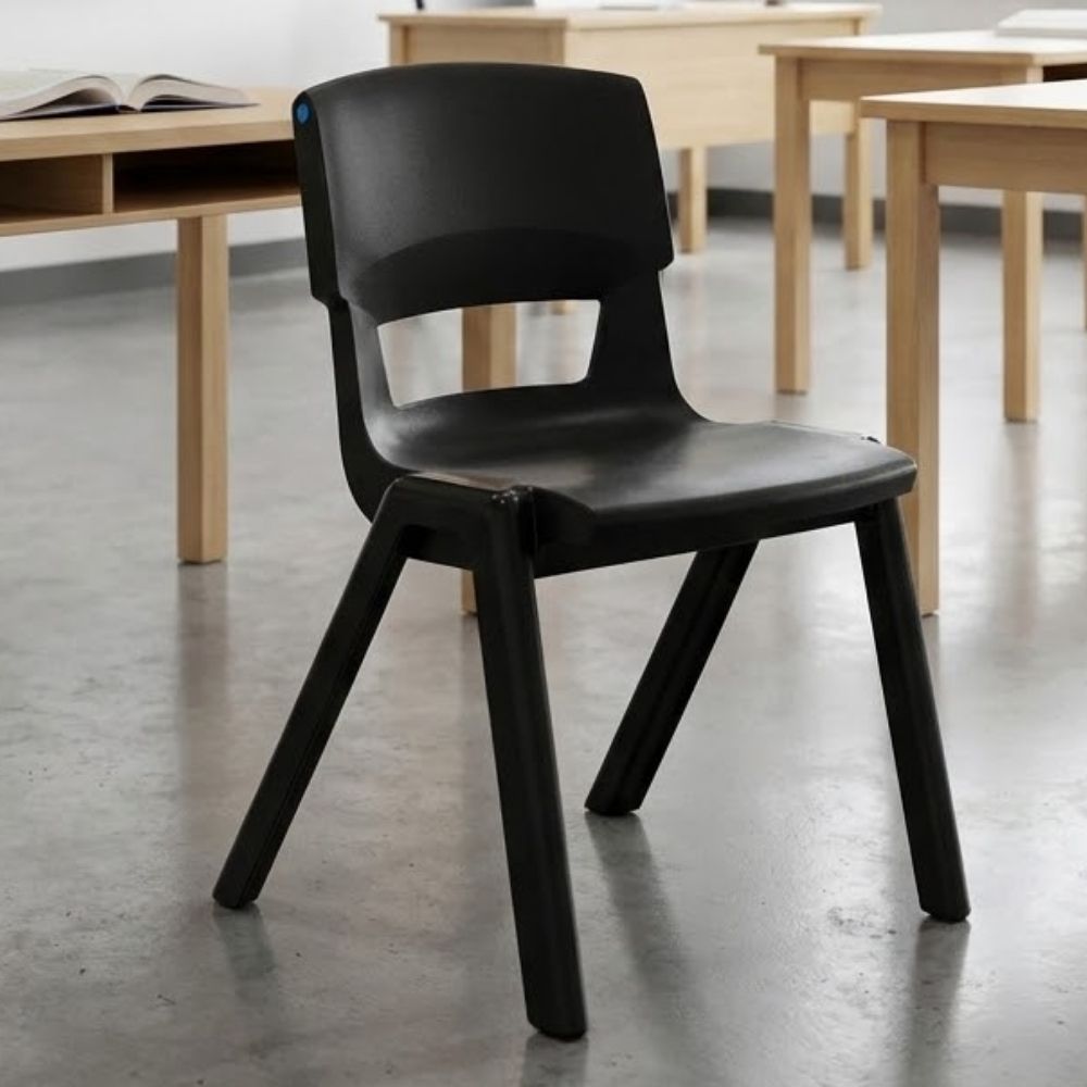 A sleek black plastic classroom chair in a minimalist learning environment, paired with light wood desks and a smooth concrete floor for a modern aesthetic.