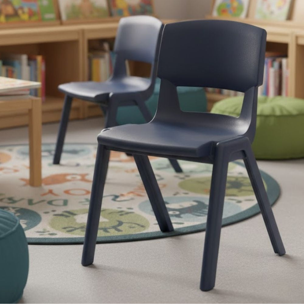 A dark grey plastic chair positioned on an illustrated alphabet rug in a cosy early years reading corner, surrounded by book displays and beanbags.