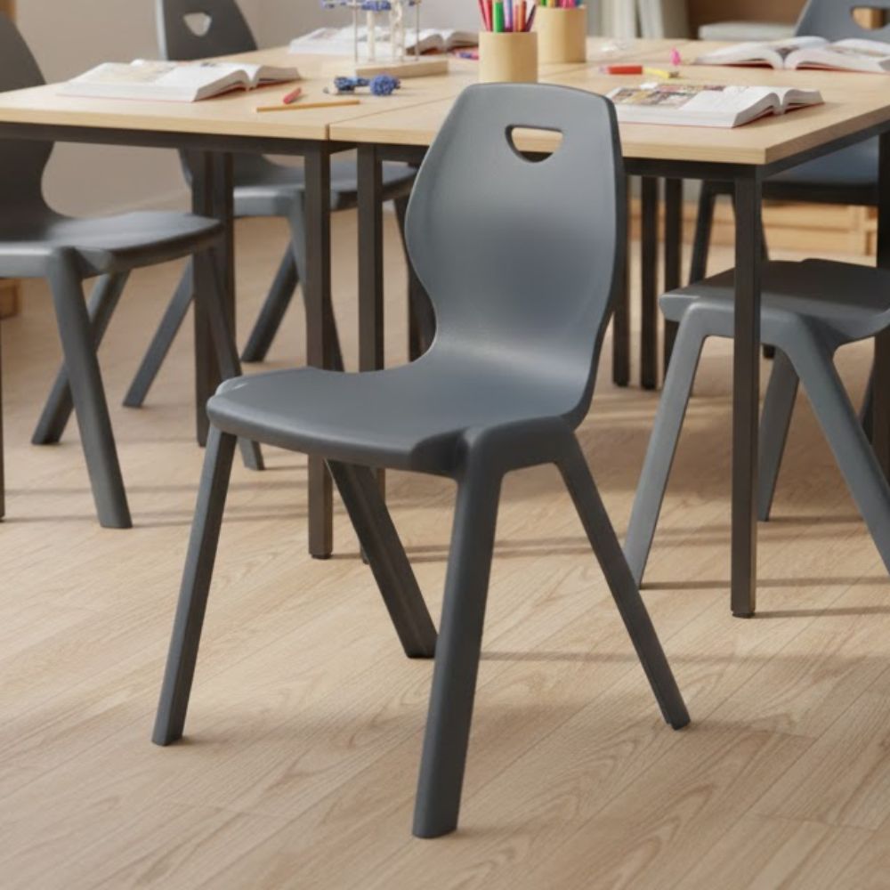 Dark grey plastic classroom chairs with contoured seats and top handle cutouts for easy movement.