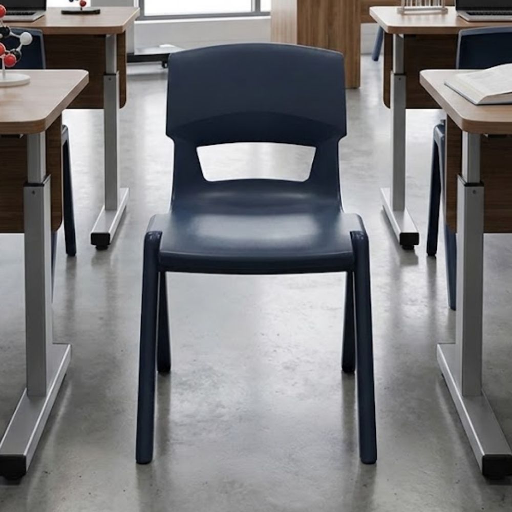 A dark grey classroom chair placed in a modern science lab setup, surrounded by adjustable desks, open textbooks and polished concrete flooring.