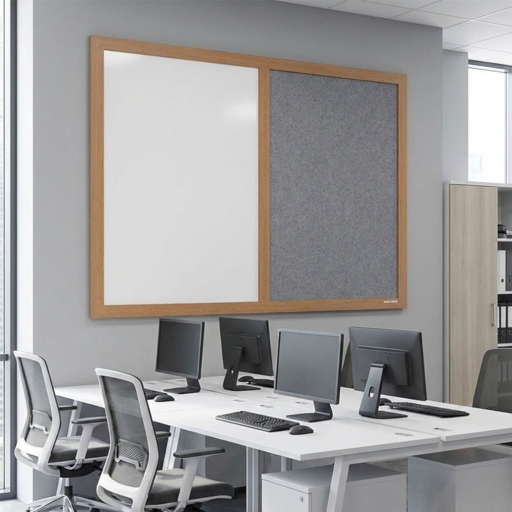 Eco-friendly combination board with grey felt panel and whiteboard surface in a wooden frame, installed on a modern open-plan office wall above desks with computer monitors.