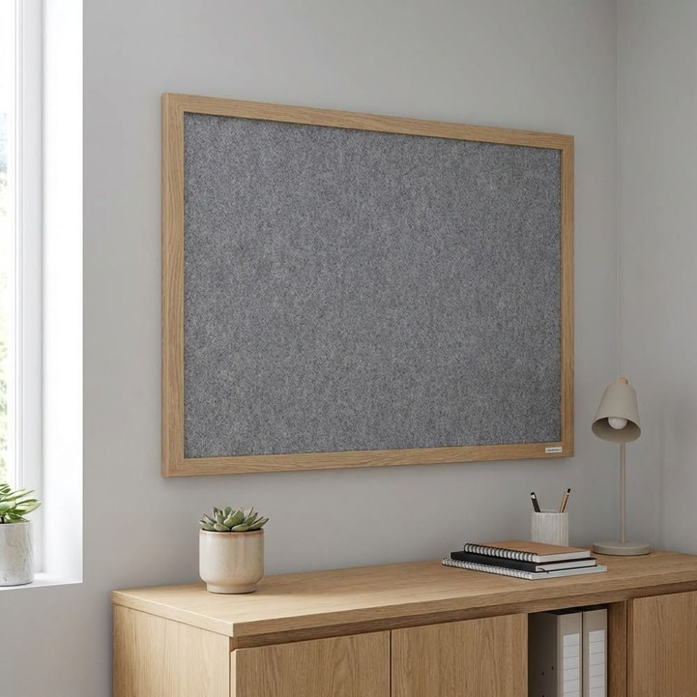 Eco-friendly 900 x 600mm grey felt noticeboard with wood effect frame, displayed on a study wall above a wooden cabinet with books and desk lamp.