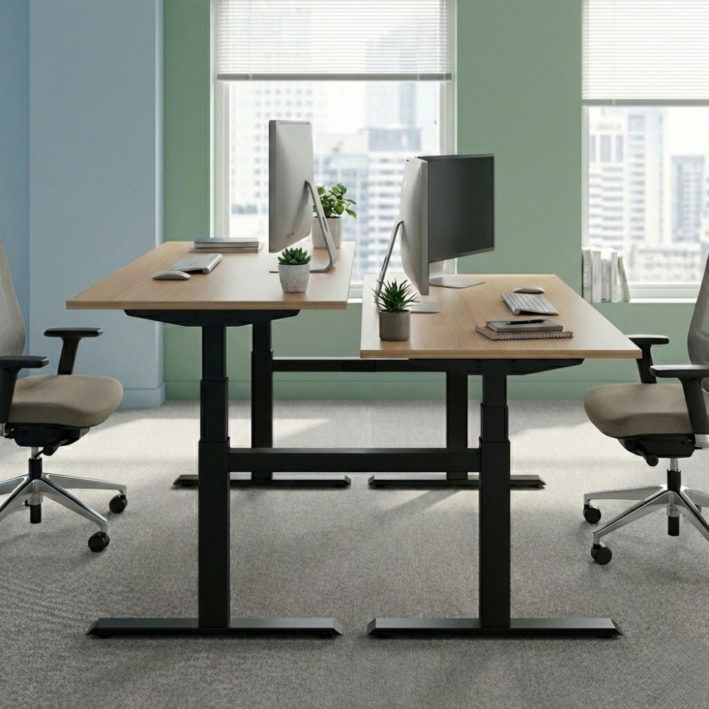 Electric height-adjustable back-to-back desks with wood-finish tops and black frames, set at different heights for sit-stand flexibility in a contemporary office with city views.