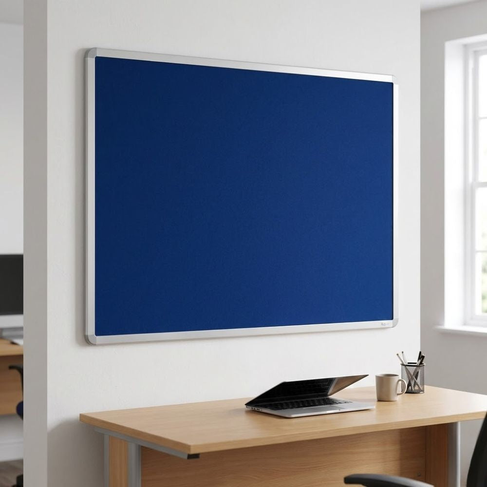 Fire resistant 1200 x 900mm blue felt noticeboard with aluminium frame, wall mounted above a desk in a classroom or office setting.