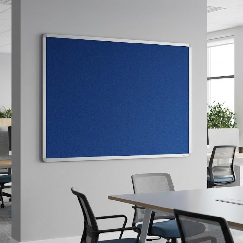 Fire resistant 1500 x 1200mm blue felt noticeboard with aluminium frame, mounted on a workplace wall above a desk and filing cabinet.