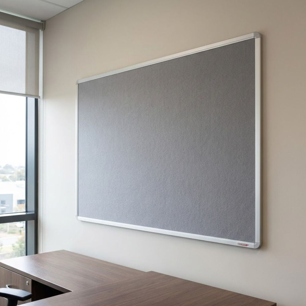 Fire resistant 1800 x 1200mm grey felt noticeboard with aluminium frame, installed on a meeting room wall above a wooden desk.