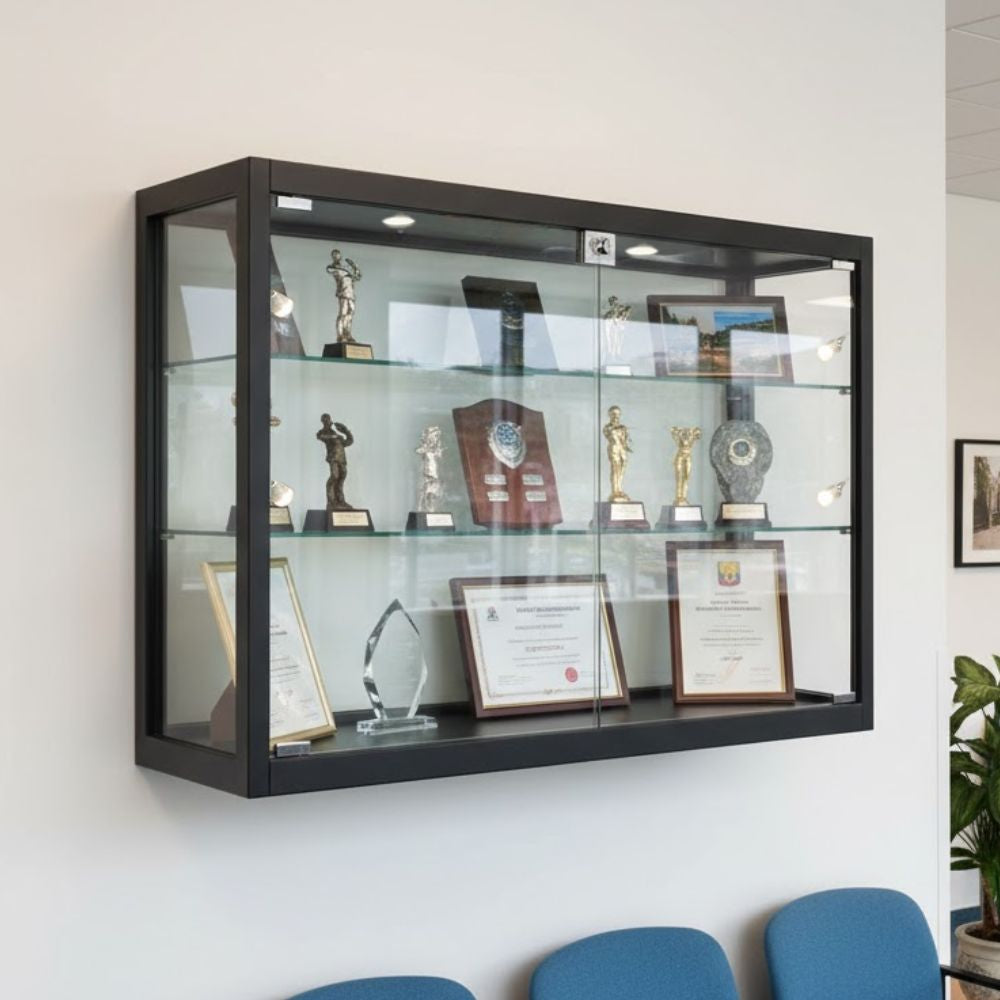 Glass wall-mounted display cabinet showcasing trophies, plaques, and framed certificates in a professional office reception area