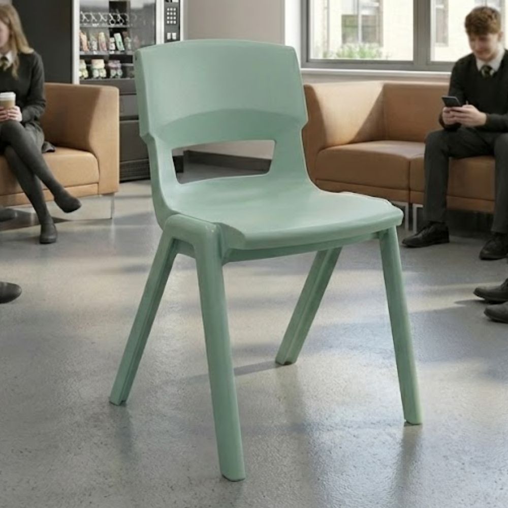 A jade‑green plastic school chair placed in a sixth form common room with soft seating and vending machines, designed for student relaxation and informal study.