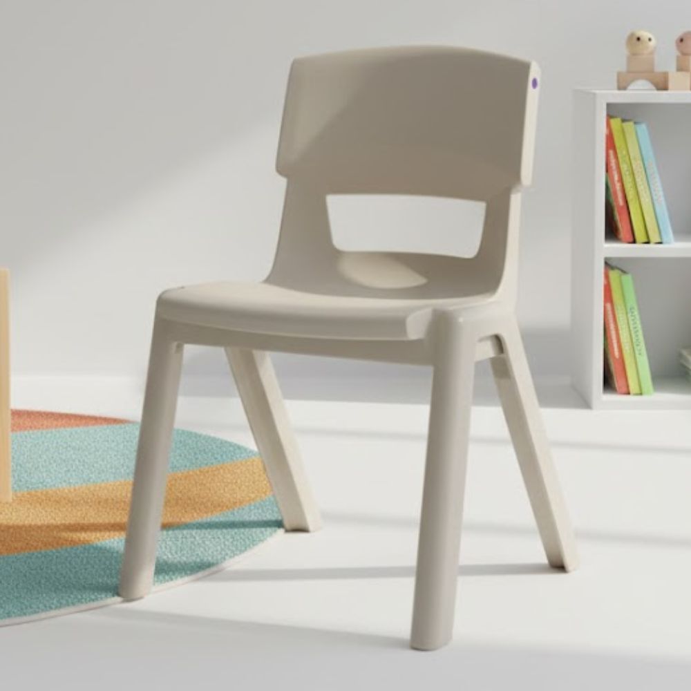 A single light‑grey plastic seat positioned next to a white bookcase filled with children’s books, in a calm reading or learning corner with soft natural lighting.