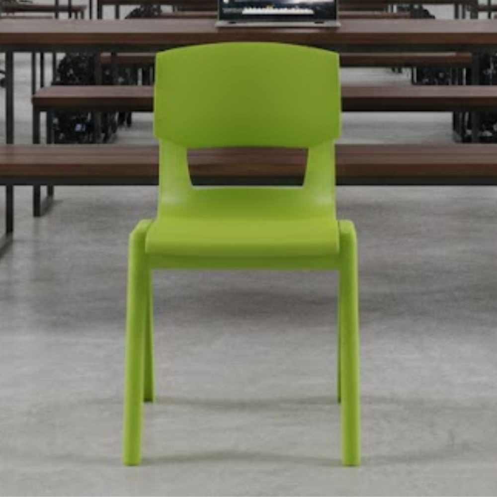 A lime green plastic chair positioned on polished concrete flooring in a spacious ICT classroom, facing long desks with open laptops.