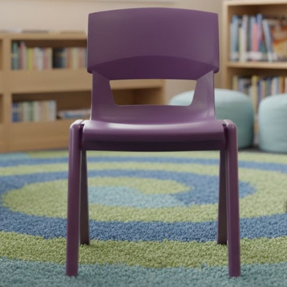 A purple school chair on a blue and green spiral rug in a reading corner, surrounded by bookshelves and soft furnishings.