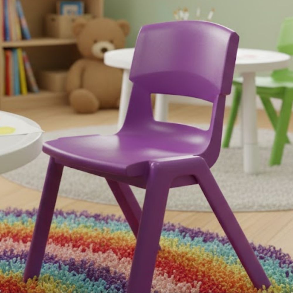 A vibrant purple nursery chair placed on a rainbow shag rug in a playful early years setting, with round activity tables and a teddy bear reading corner.
