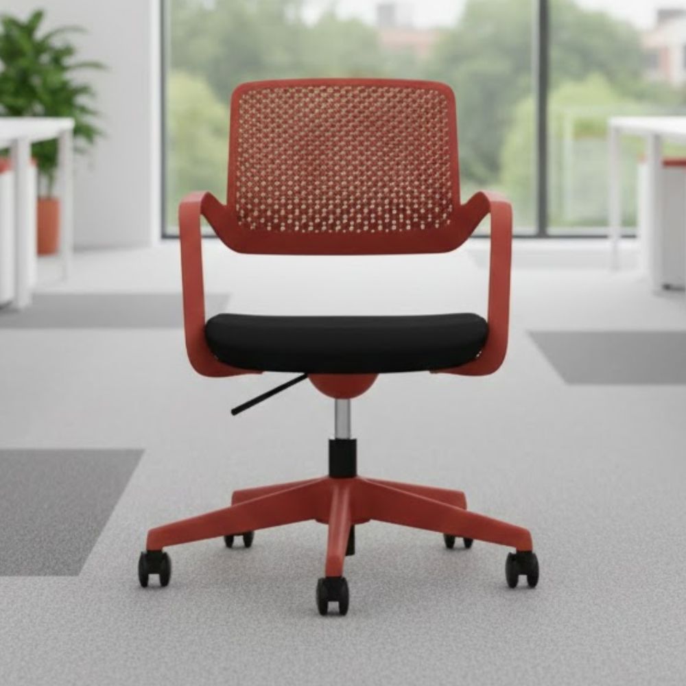 Red swivel office chair with perforated plastic backrest, black cushioned seat and five star base with castors, positioned in a bright contemporary workspace with large windows and greenery