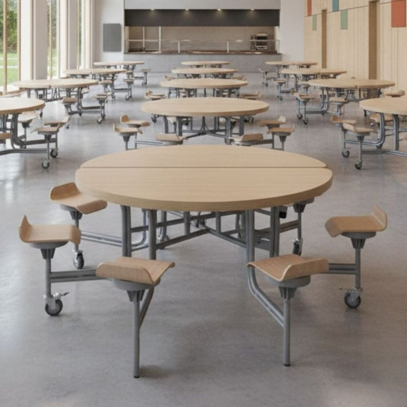 Woodgrain finish round dining tables with integrated sculpted wooden stools on castors, arranged throughout a large, well-lit school refectory.