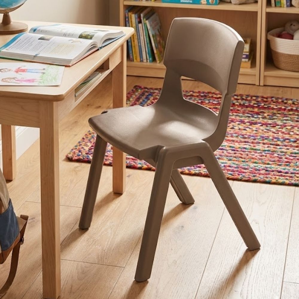 
Taupe plastic study chair with curved backrest in a child’s reading area with bookshelf and rug
