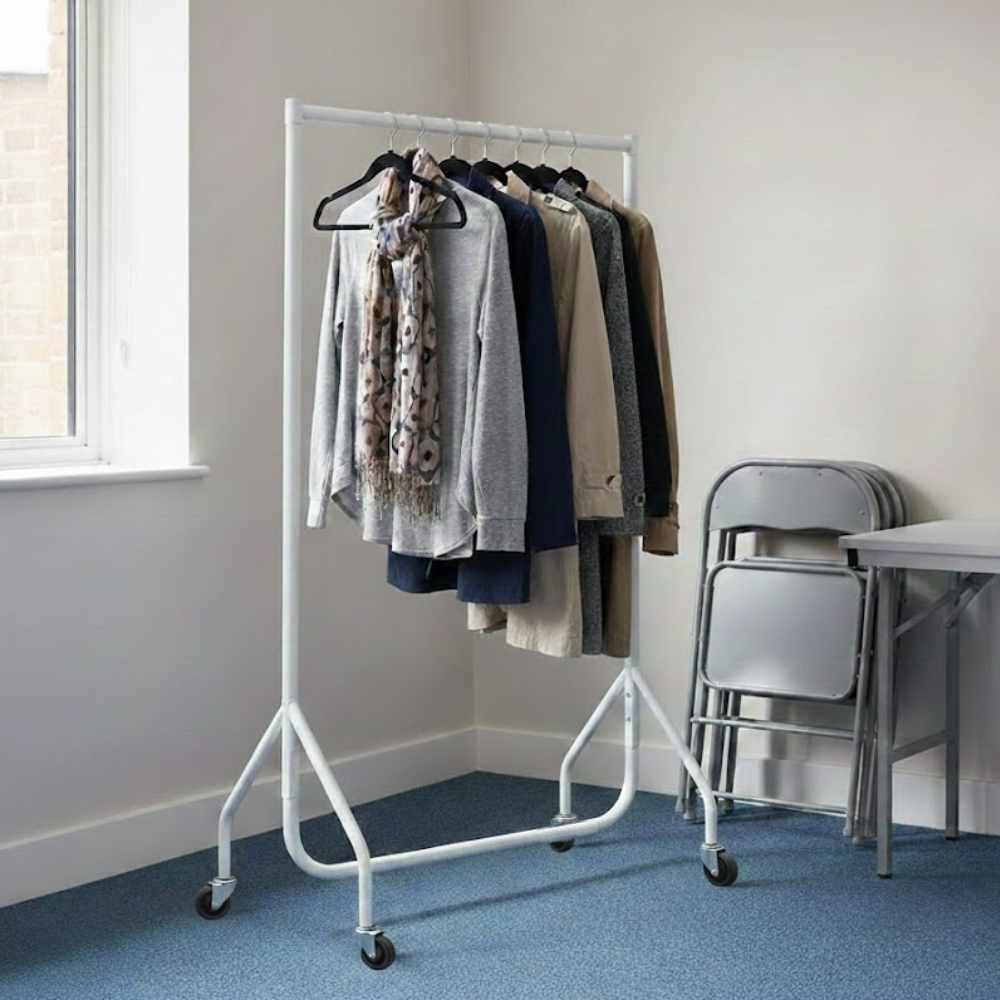 White wheeled clothes rail holding neatly arranged coats, jumpers and scarves in a bright room with folded chairs nearby.